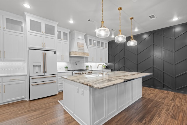 kitchen with white cabinetry, light stone counters, high end white fridge, and premium range hood