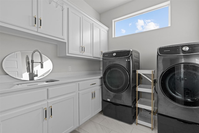 clothes washing area with cabinets, light tile patterned floors, washer and clothes dryer, and sink