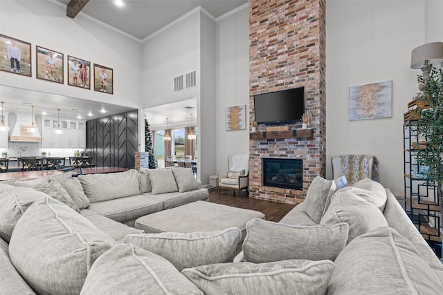 living room featuring a high ceiling, crown molding, a brick fireplace, and hardwood / wood-style floors