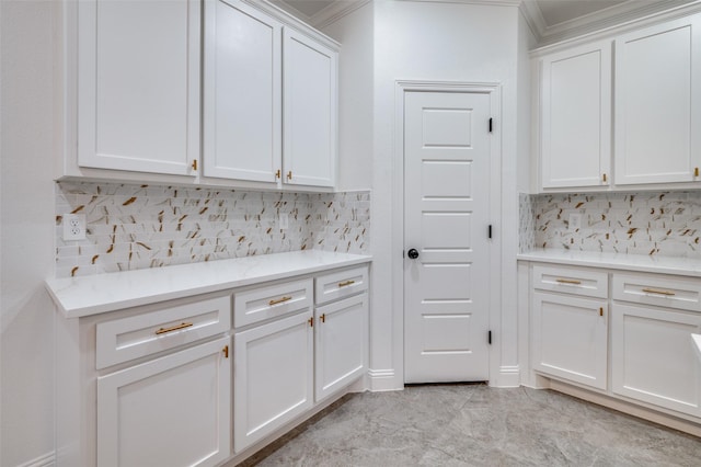 kitchen featuring backsplash, ornamental molding, and white cabinets