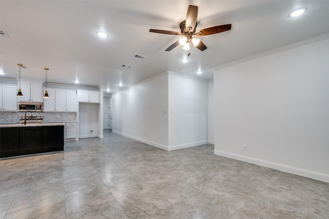 unfurnished living room with sink, crown molding, and ceiling fan