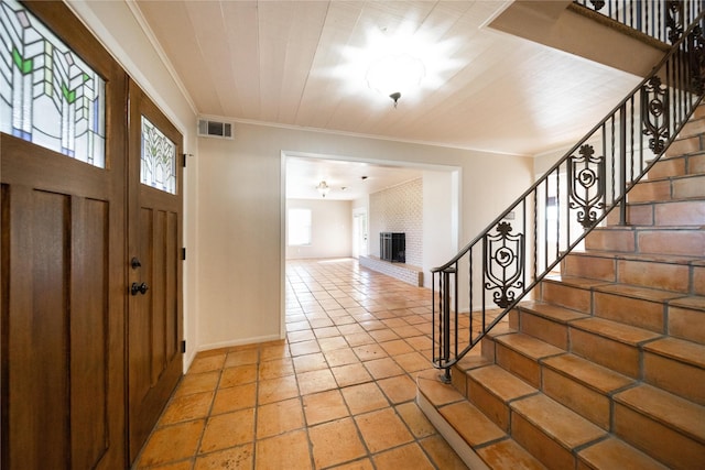 foyer entrance featuring a brick fireplace and ornamental molding