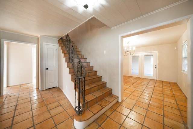 stairway with a chandelier, french doors, and crown molding