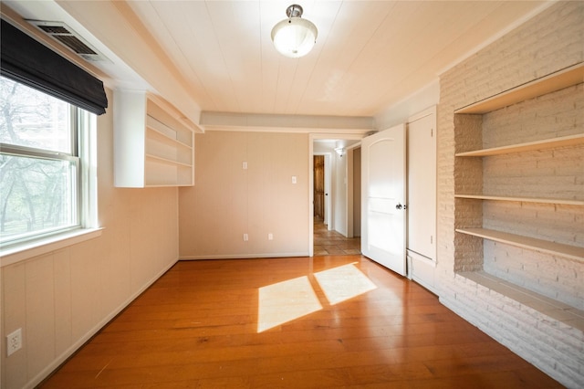 unfurnished bedroom featuring light hardwood / wood-style flooring and brick wall