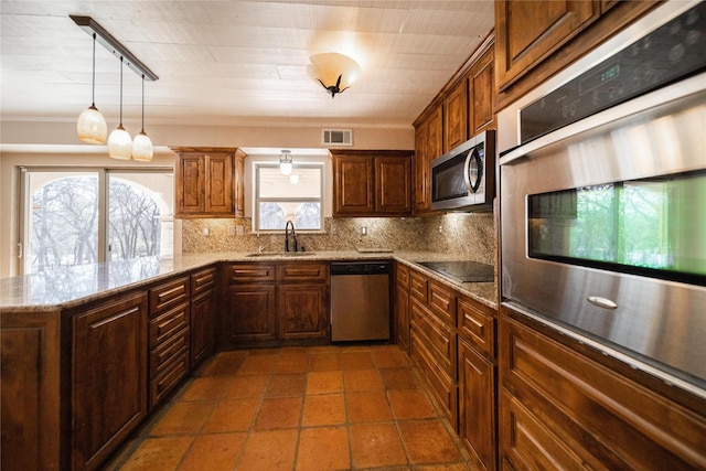 kitchen with kitchen peninsula, appliances with stainless steel finishes, rail lighting, tasteful backsplash, and sink