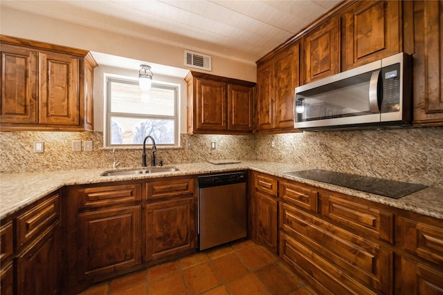 kitchen featuring sink, decorative backsplash, light stone counters, and stainless steel appliances