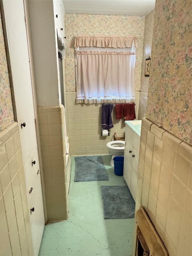 bathroom featuring tile walls and toilet