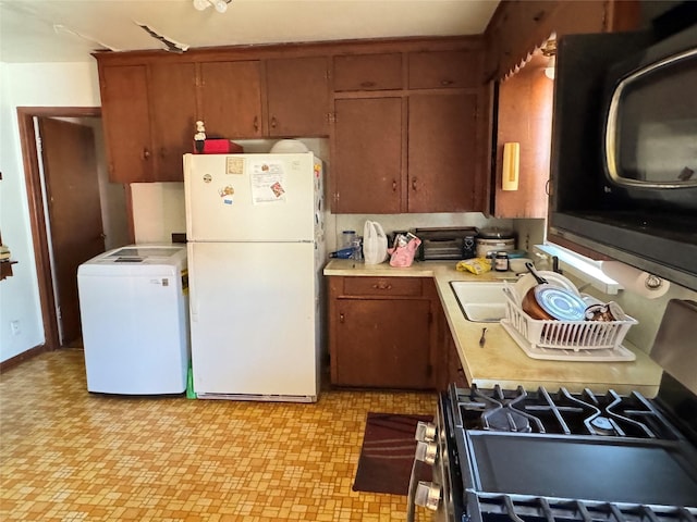 kitchen featuring white refrigerator, sink, and washer / clothes dryer