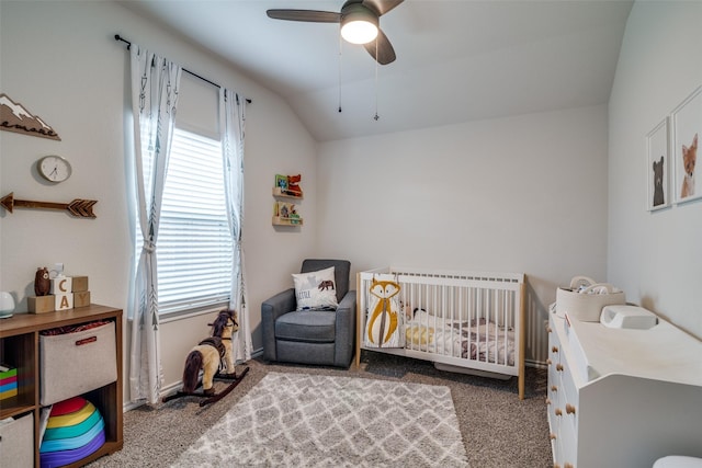 bedroom with vaulted ceiling, a nursery area, ceiling fan, and carpet