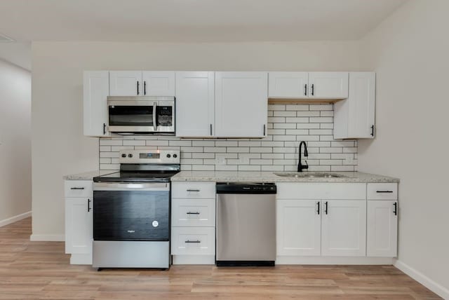 kitchen with light stone countertops, white cabinetry, sink, and appliances with stainless steel finishes