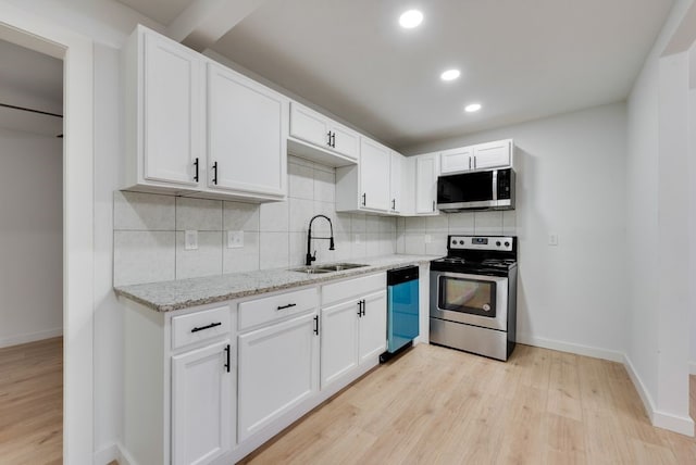 kitchen featuring stainless steel appliances, white cabinetry, light stone countertops, and backsplash