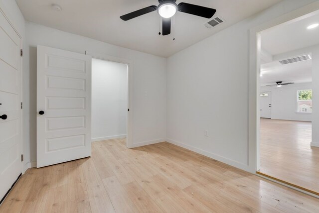 empty room with ceiling fan and light hardwood / wood-style flooring