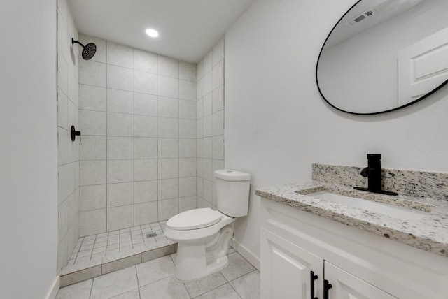 bathroom featuring tile patterned flooring, vanity, a tile shower, and toilet