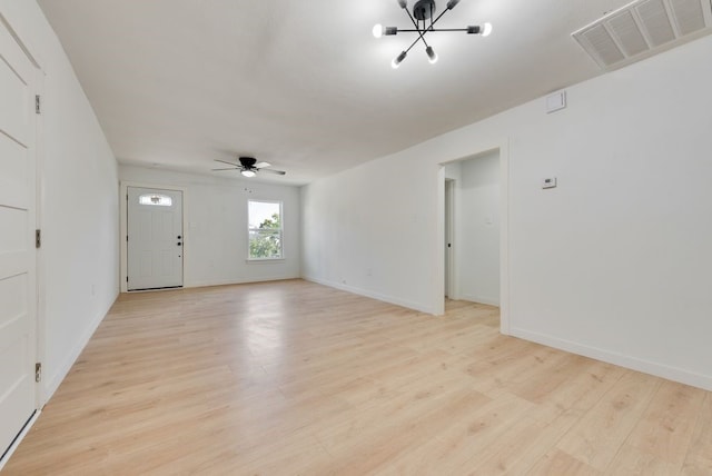 unfurnished living room with ceiling fan with notable chandelier and light hardwood / wood-style flooring