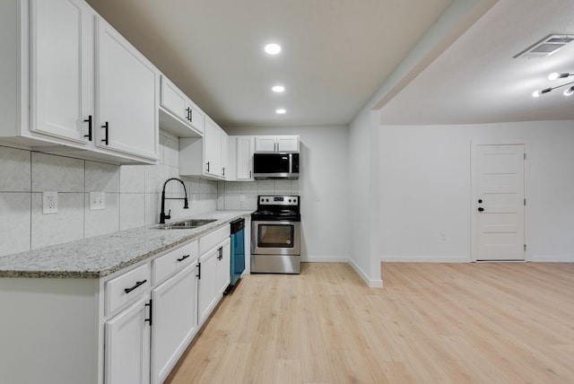 kitchen featuring tasteful backsplash, sink, white cabinets, light stone counters, and stainless steel appliances