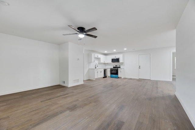 unfurnished living room featuring ceiling fan, light wood-type flooring, and sink