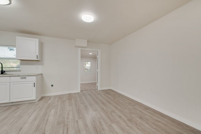 interior space featuring white cabinets, plenty of natural light, light wood-type flooring, and sink