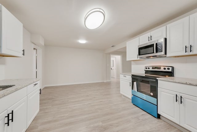 kitchen with light stone countertops, white cabinetry, appliances with stainless steel finishes, and light hardwood / wood-style flooring