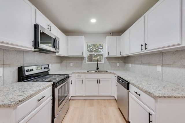 kitchen with white cabinets, decorative backsplash, sink, and stainless steel appliances