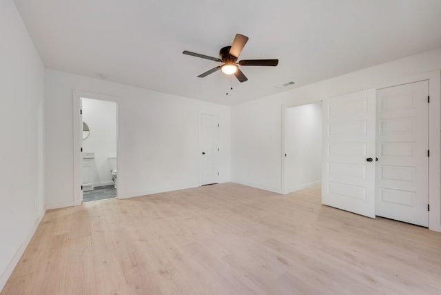 unfurnished bedroom featuring a closet, light wood-type flooring, ensuite bathroom, and ceiling fan