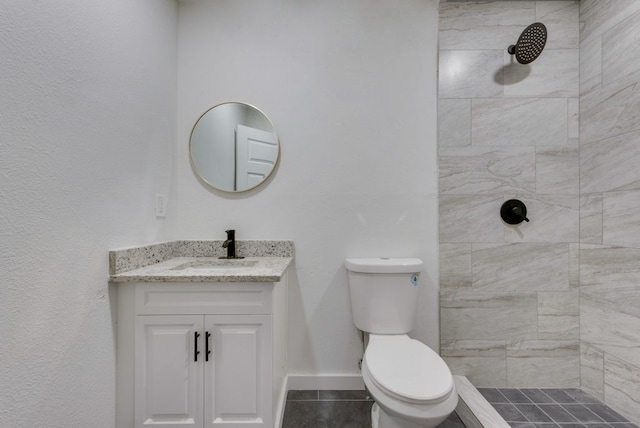 bathroom with tiled shower, vanity, and toilet