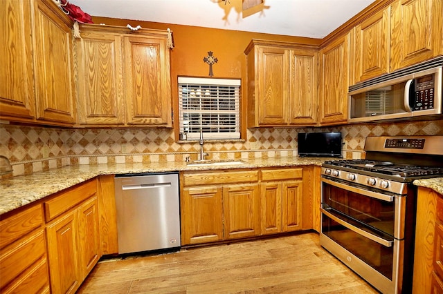 kitchen with light stone countertops, decorative backsplash, sink, and stainless steel appliances