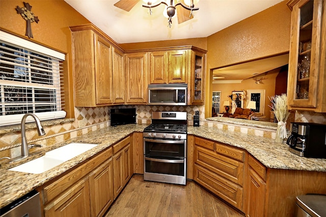 kitchen featuring appliances with stainless steel finishes, light hardwood / wood-style floors, light stone counters, and sink