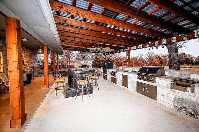 view of patio / terrace with area for grilling, an outdoor stone fireplace, ceiling fan, sink, and a grill