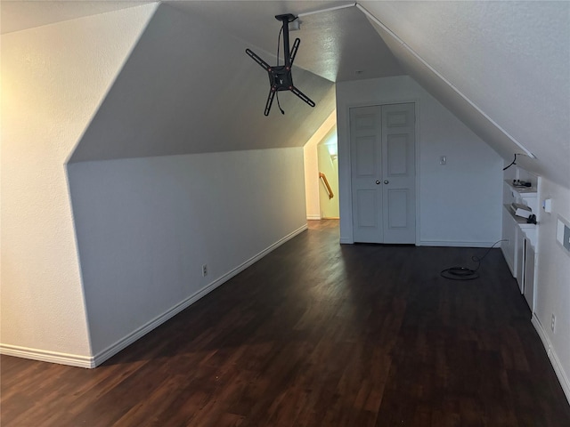 bonus room featuring a textured ceiling, dark wood-type flooring, and vaulted ceiling