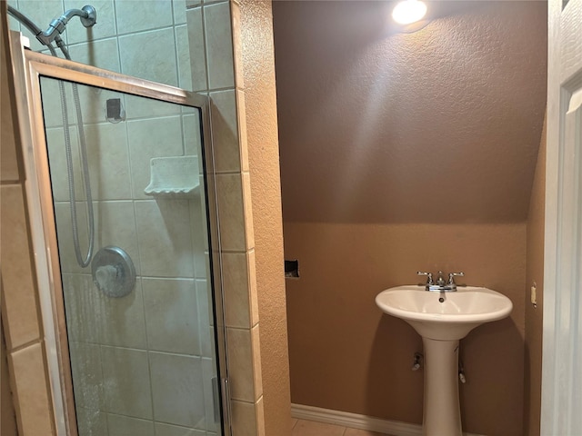 bathroom featuring tile patterned flooring, a shower with shower door, and lofted ceiling