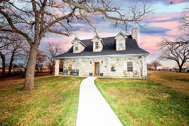 cape cod home with a patio area and a yard