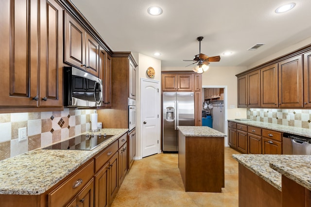 kitchen featuring light stone counters, appliances with stainless steel finishes, ceiling fan, and a kitchen island