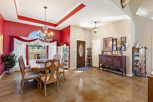 dining area featuring a raised ceiling, concrete flooring, and a notable chandelier