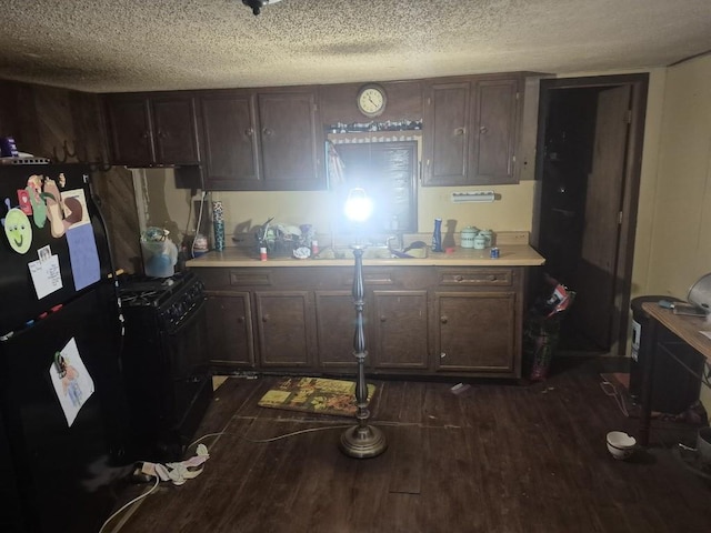 kitchen featuring a textured ceiling, dark brown cabinetry, dark wood-type flooring, and black appliances