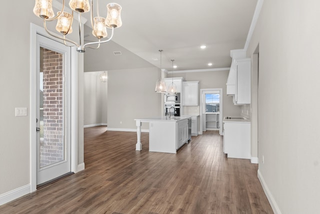 kitchen with white cabinetry, stainless steel appliances, a center island with sink, dark hardwood / wood-style flooring, and decorative light fixtures