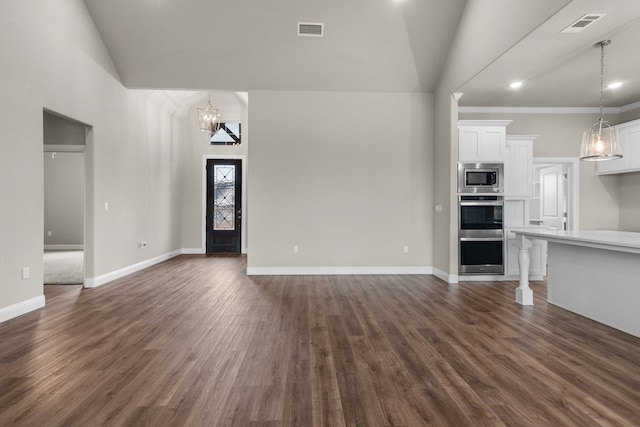 unfurnished living room with an inviting chandelier, lofted ceiling, dark hardwood / wood-style flooring, and crown molding