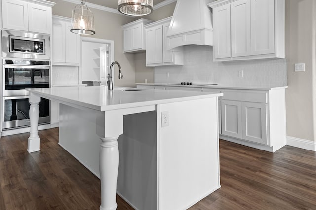 kitchen featuring sink, white cabinetry, hanging light fixtures, a kitchen island with sink, and custom exhaust hood