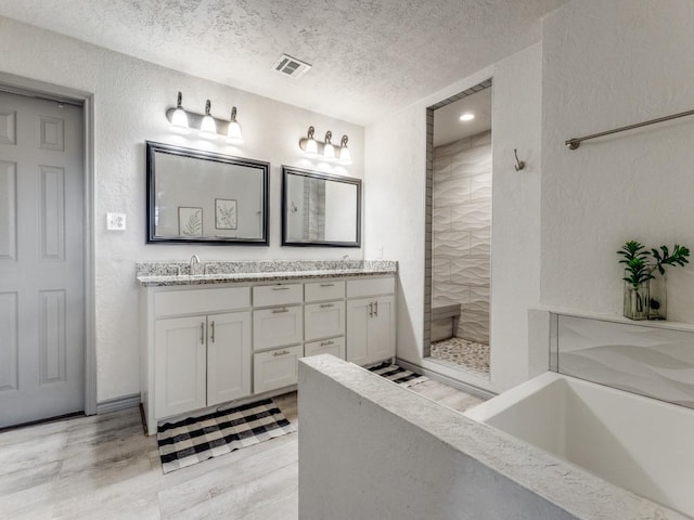 bathroom featuring vanity, a textured ceiling, and tiled shower