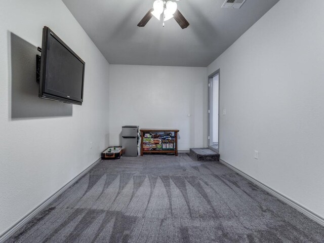 unfurnished living room featuring ceiling fan and dark carpet