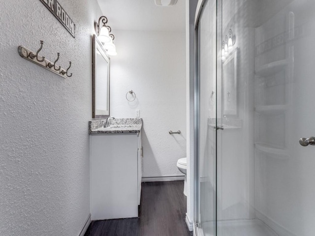 bathroom featuring hardwood / wood-style floors, vanity, an enclosed shower, and toilet