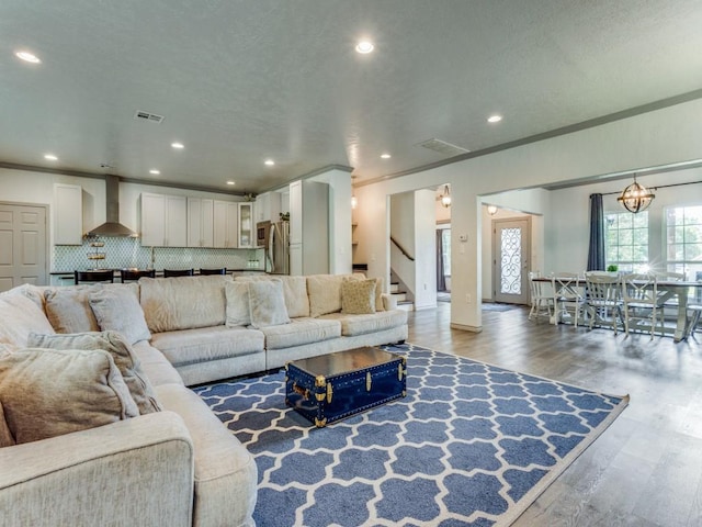 living room with a notable chandelier, wood-type flooring, and ornamental molding