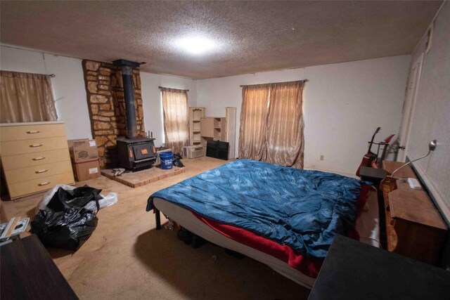 bedroom with a wood stove, a textured ceiling, and carpet floors