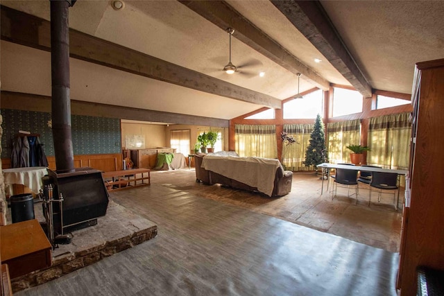 bedroom with lofted ceiling with beams, a wood stove, and a textured ceiling