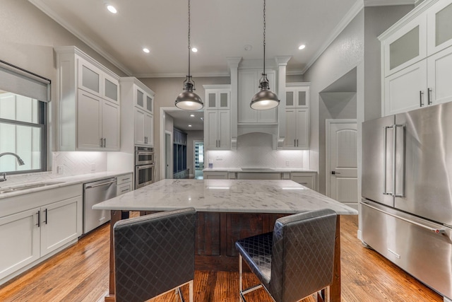 kitchen with pendant lighting, white cabinetry, sink, a center island, and stainless steel appliances