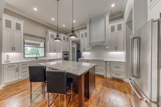 kitchen with a center island, stainless steel appliances, decorative backsplash, white cabinets, and light wood-type flooring