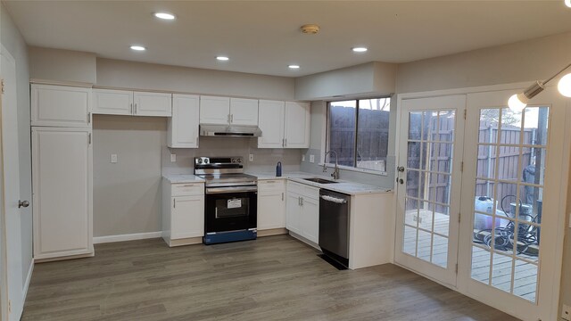 kitchen with sink, light hardwood / wood-style flooring, decorative backsplash, white cabinets, and appliances with stainless steel finishes