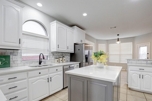 kitchen with sink, hanging light fixtures, a kitchen island, white cabinetry, and stainless steel appliances