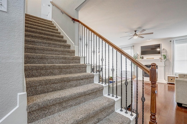 stairway with wood-type flooring and ceiling fan