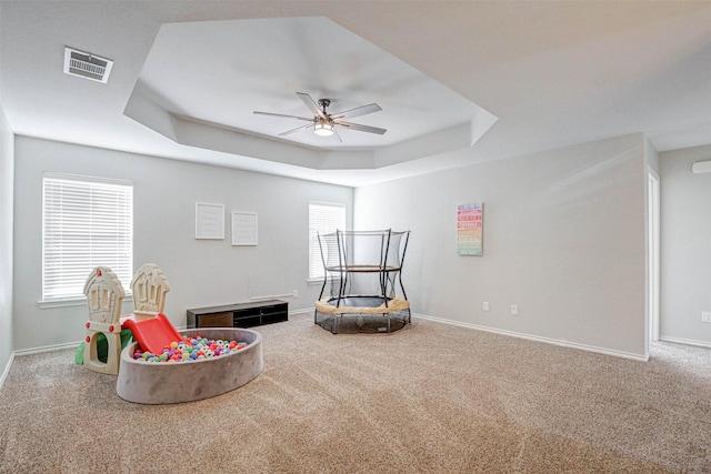 sitting room with a tray ceiling, ceiling fan, and carpet flooring