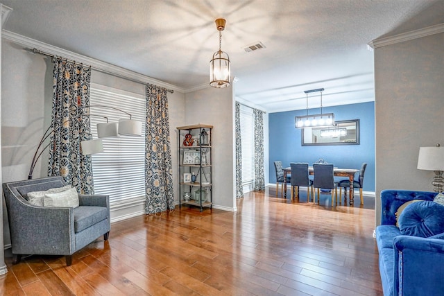 living area with a chandelier, a textured ceiling, hardwood / wood-style flooring, and crown molding